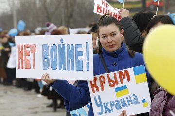An anti-war protester holds placards during a rally on a road in Simferopol