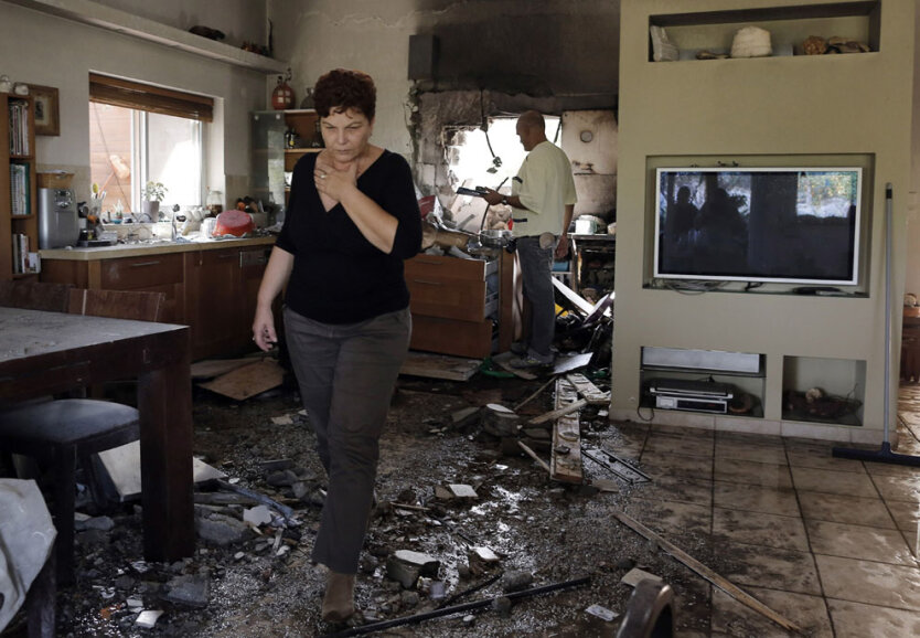 Израильская женщина идет через поврежденный дом, 16 ноября 2012 года