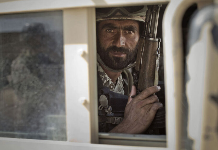 Боец элитного отряда афганской полиции гражданского порядка смотрит в окно из бронеавтомобиля во время патрулирования в городе Марджа, провинция Гильменд