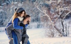 happy loving couple walking in snowy winter forest, spending christmas vacation together. Outdoor seasonal activities.