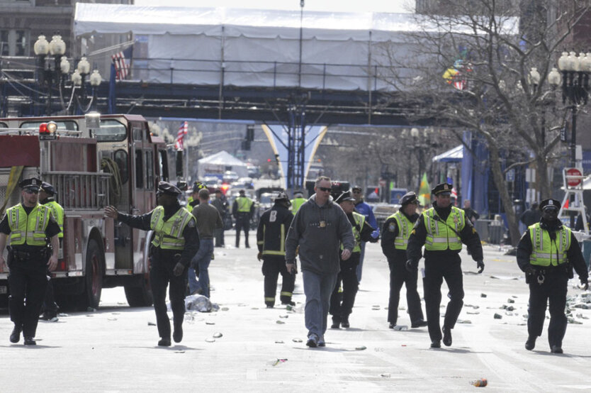 Офицеры полиции эвакуируют посетителей одного из самых известных в мире марафонов, где в понедельник, 15 апреля 2013 года прозвучало два взрыва. В это время на улицах города Бостон находились десятки тысяч людей. (Reuters/Neal Hamberg)  