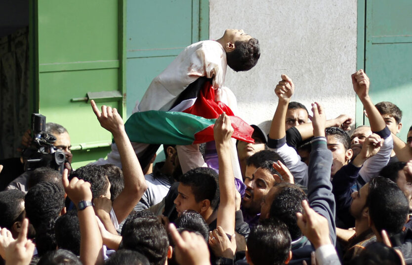Палестинцы поднимают тело погибшего ребенка во похорон в городе Газа, 19 ноября 2012 года. 