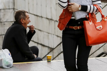 A man eats his sandwich as he begs money near an underground passage in Kiev