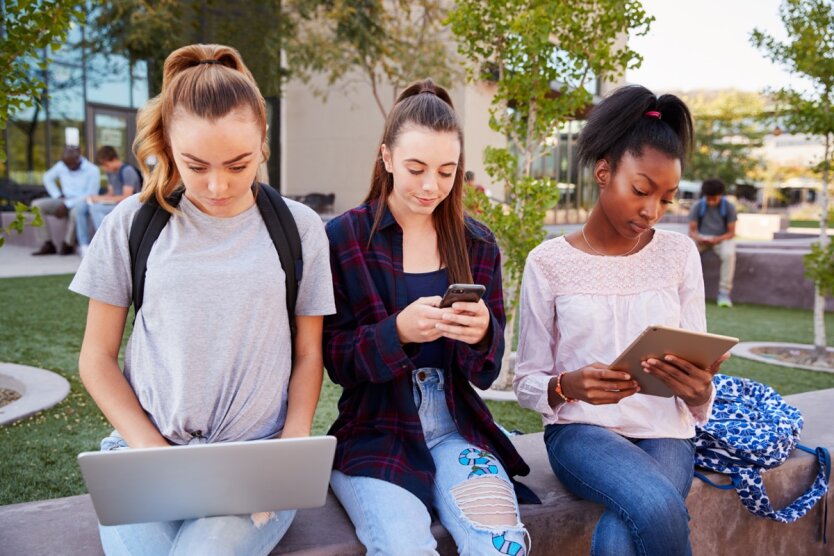Группа девочек-подростков, использующая свои электронные устройства.