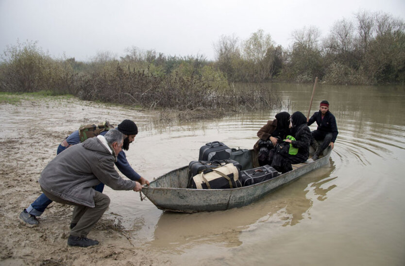 Район города Даркуш, Северная Сирия. Повстанцы отталкивают от берега лодку с двумя женщинами, которые собрались сбежать в Турцию по реке Оронт