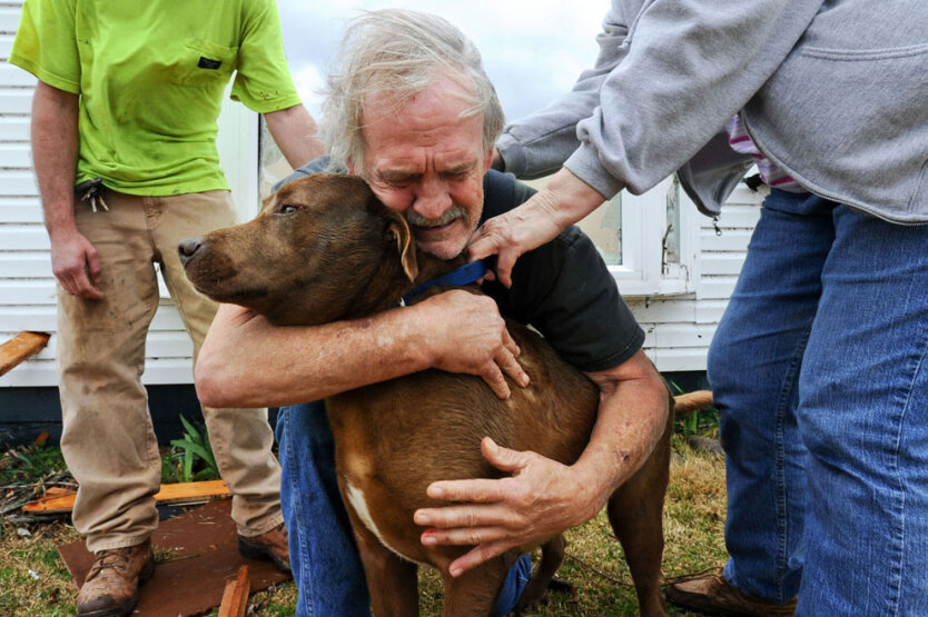 Грег Кук обнимает свою собаку по кличке Коко после её освобождения из-под развалин дома Грега в городе Ист Лаймстоун, штат Алабама, США