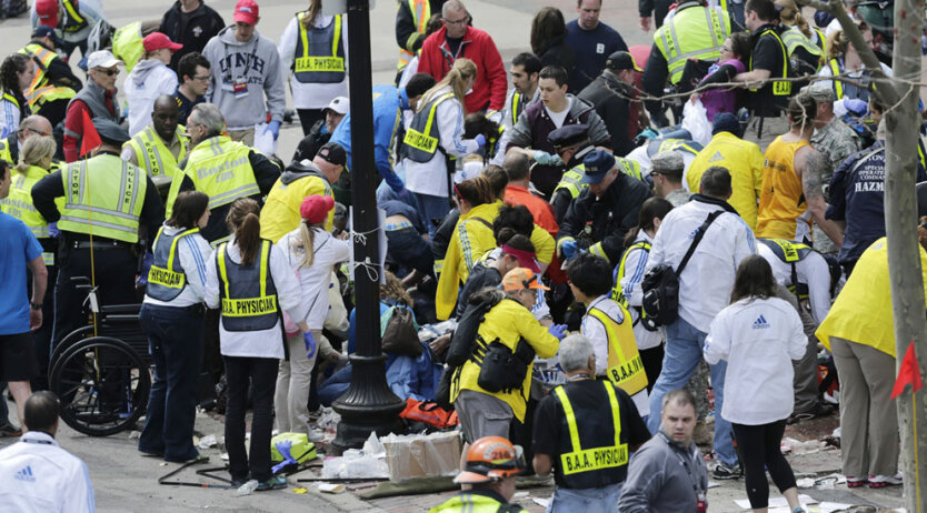 Медицинские рабтники оказывают помощь пострадавшим от взрыва во время проведения Бостонского марафона. Всего прогремело два взрыва. Власти сразу же приступили к эвакуации зрителей и пострадавших. (AP Photo/Charles Krupa)  
