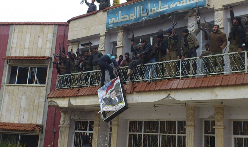 Повстанцы из батальона «Аль-Фарук» срывают плакат президента Башара аль-Асада с фасада захваченного ими военного госпиталя в Халфайя недалеко от города Хама