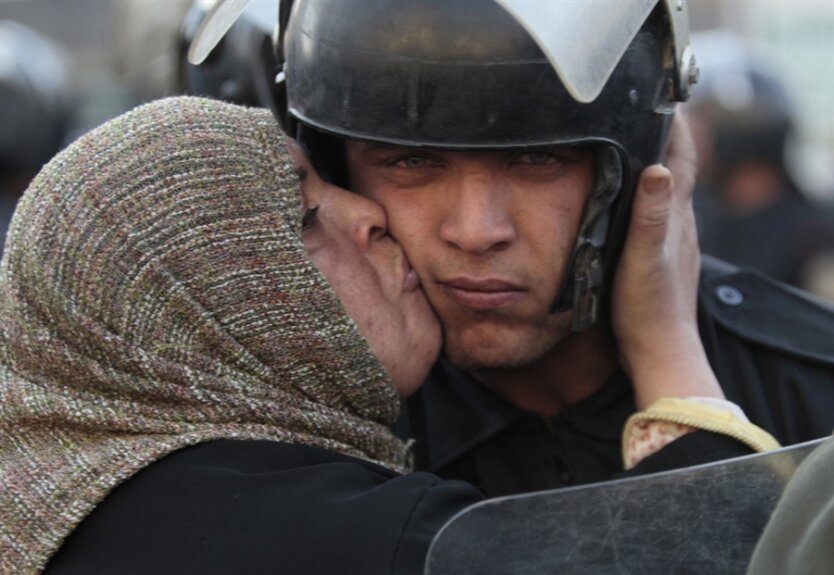 Участница антиправительственной демонстрации в Египте целует полицейского. Фото: Lefteris Pitarakis / AP via MSN с сайта metkere.com