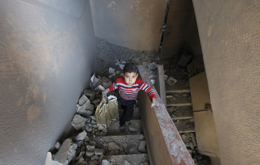 Палестинский мальчик поднимается по лестнице из дома, разрушенного в воскресенье израильскими парнями  в городе Газа