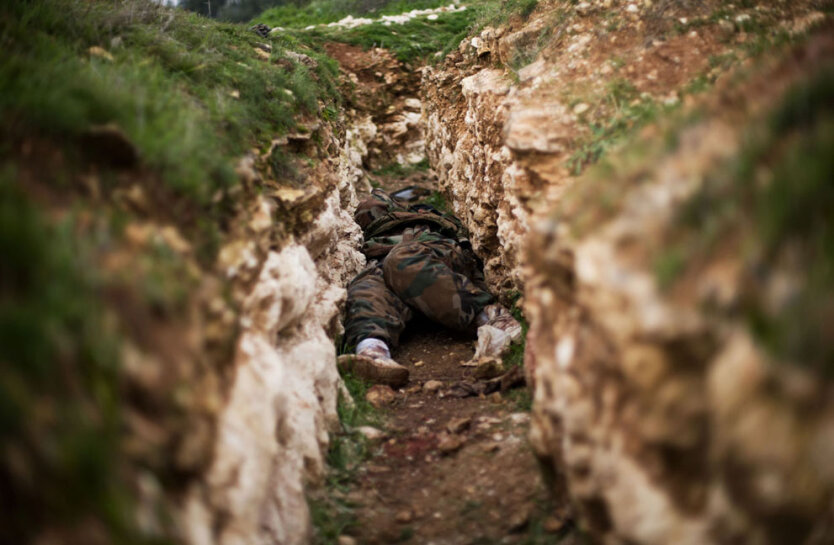 Труп сирийского солдата лежит в окопе после боя возле военной академии