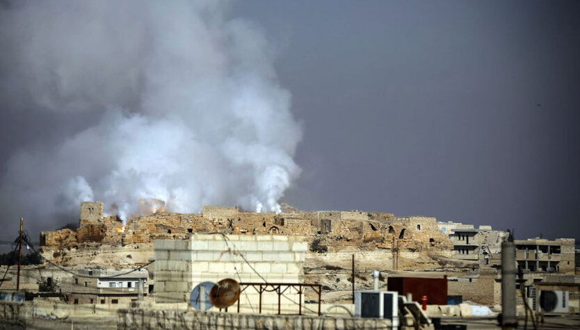 Дым и огонь поднимаются над древнеримской крепостью Калат-ан-Нуман в городе Маарет-ан-Нуман, провинция Идлиб