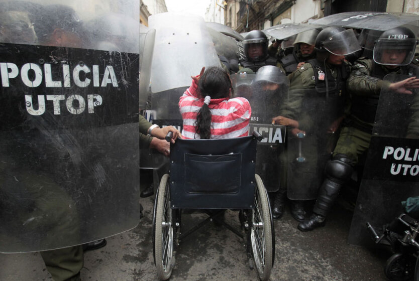 Женщина в инвалидном кресле в столкновении с полицией охраны общественного порядка в центре Ла-Паса, Боливия. 