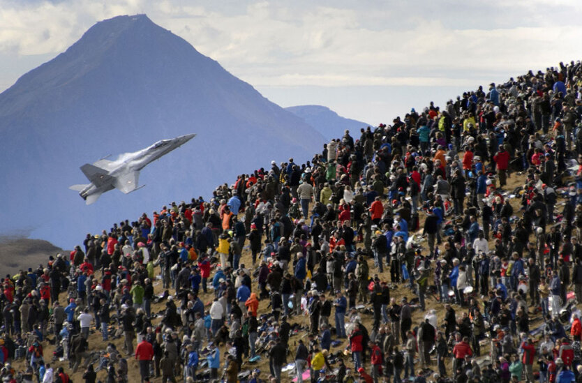 . Бернские Альпы, Швейцария. Люди наблюдаю за показательным полетом штурмовика F/A-18 Hornet во время авиашоу Swiss Air Force. 