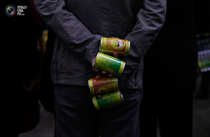 13. В центре задымленного Пекина мужчина держит в руках банки со свежим воздухом, которые раздает китайский мультимиллионер Чен Ганбяо. (Barry Huang / Reuters)