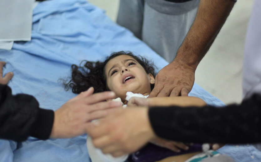 Раненая палестинская малышка  лежит на больничной койке после  авиаудара в северной части сектора Газа