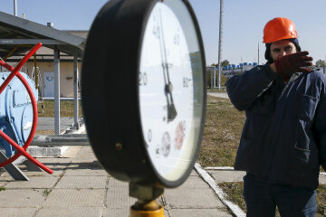 A worker stands near a pressure gauge and a valve at a gas compressor station and underground gas storage facility in the village of Mryn