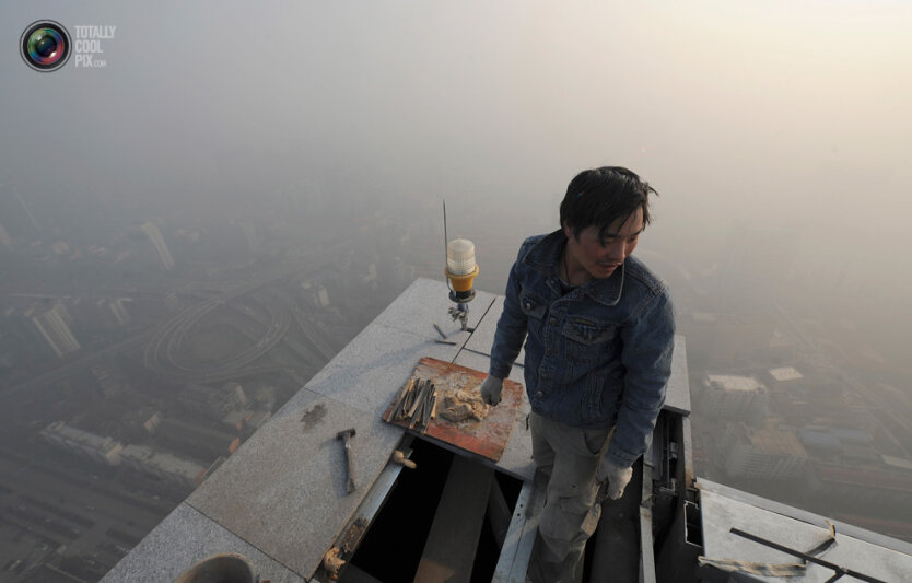 8. Рабочий на верху строящегося небоскреба в задымленном городе Хэфэй. (Jianan Yu / Reuters)