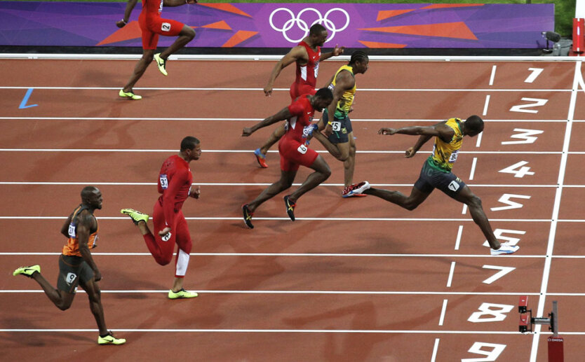 Усэин Болт из  Ямайки пересекает финишную черту и выигрывает золото в мужском 100-метровом финале на лондонской Олимпиаде
