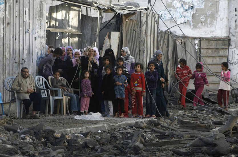  Палестинцы скорбно стоят у обломков здания Аттия Абу Инкары, лидера боевиков ХАМАС