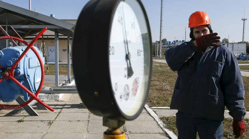 A worker stands near a pressure gauge and a valve at a gas compressor station and underground gas storage facility in the village of Mryn