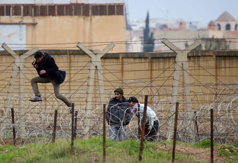 Сириец перепрыгивает через проволочные заграждения во время попытки пересечь государственную границу, проходящую между сирийским приграничным городом Рас-аль-Айн и турецким городом Джейланпынар, провинция  Шанлыурфа